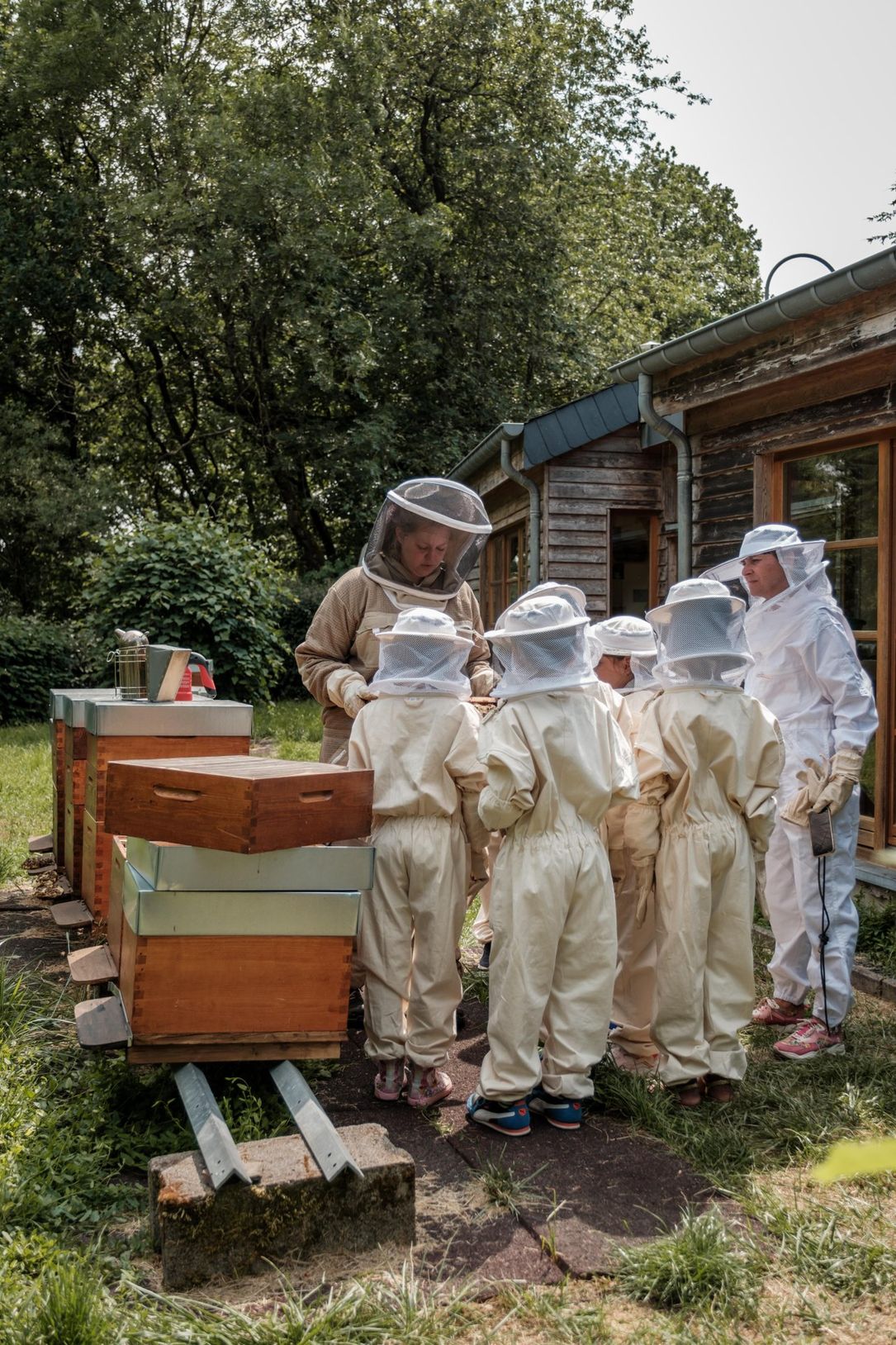 Children in protective beekeeping suits learning about honey production with a beekeeper at Robbesscheier in Munshausen