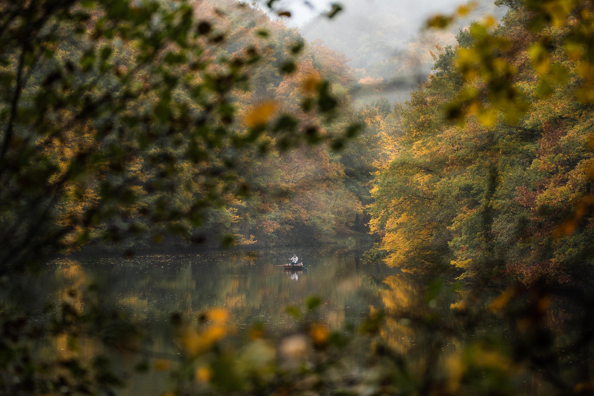 Homme ramant sur le lac de la Haute-Sûre entouré de paysages colorés d’automne dans l’Éislek, au Luxembourg. 