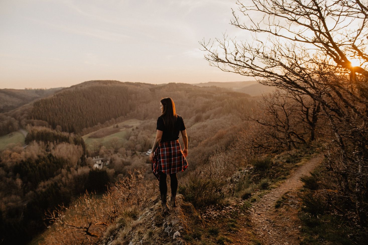 A woman stands at a viewpoint in the summer. She gazes into the distance and admires the nature surrounding her.