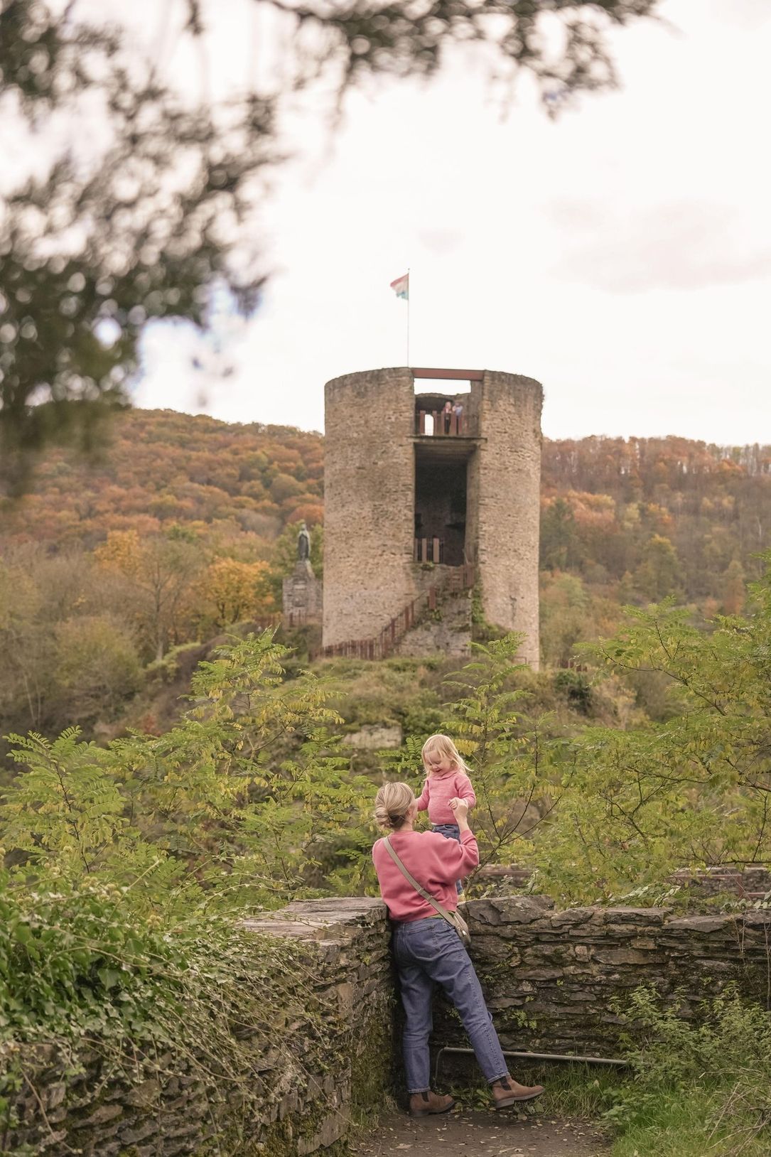 Mutter und Kleinkind erkunden die mittelalterlichen Ruinen der Burg Esch-sur-Sûre im Éislek, Luxemburg.