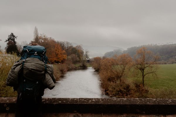 Homme avec sac à dos de randonnée admirant la vue panoramique sur le Lee Trail dans l’Éislek, au Luxembourg. 