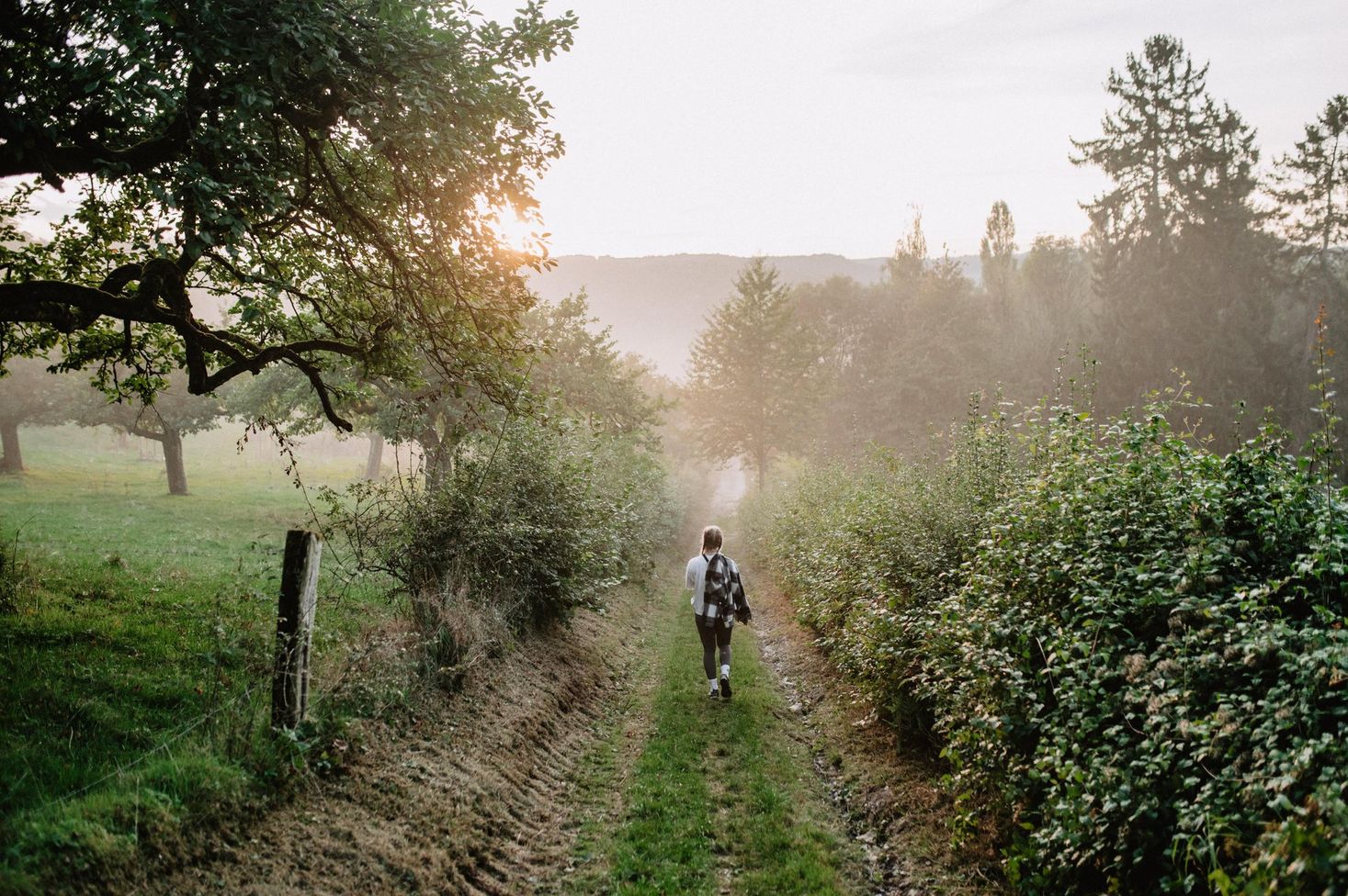 Young woman hiking on the Éislek Pad Diekirch trail on a misty autumn morning in Luxembourg.