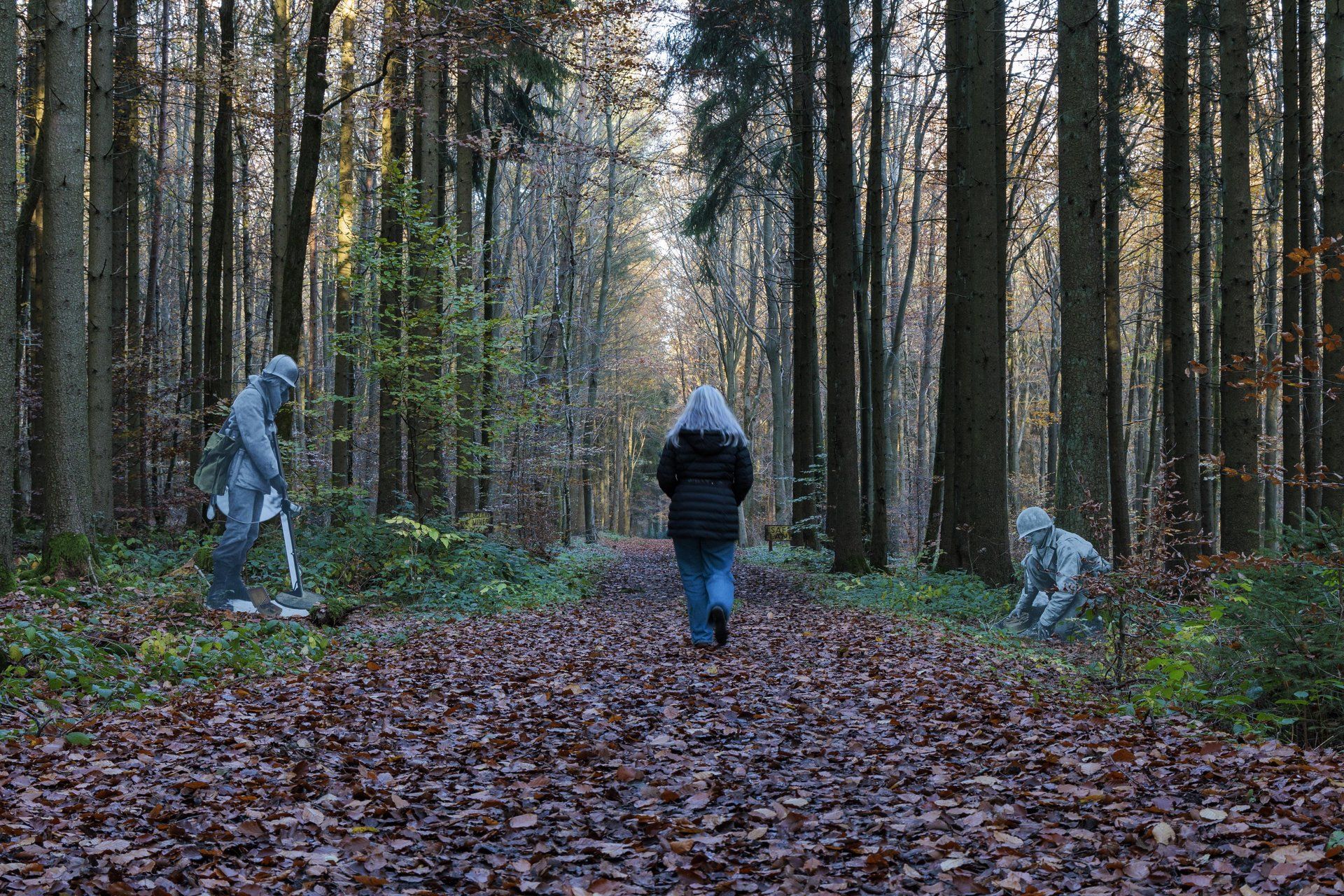Vrouw wandelt over het Schumannseck-herdenkingspad in Éislek, Luxemburg, omringd door herfstkleuren. 