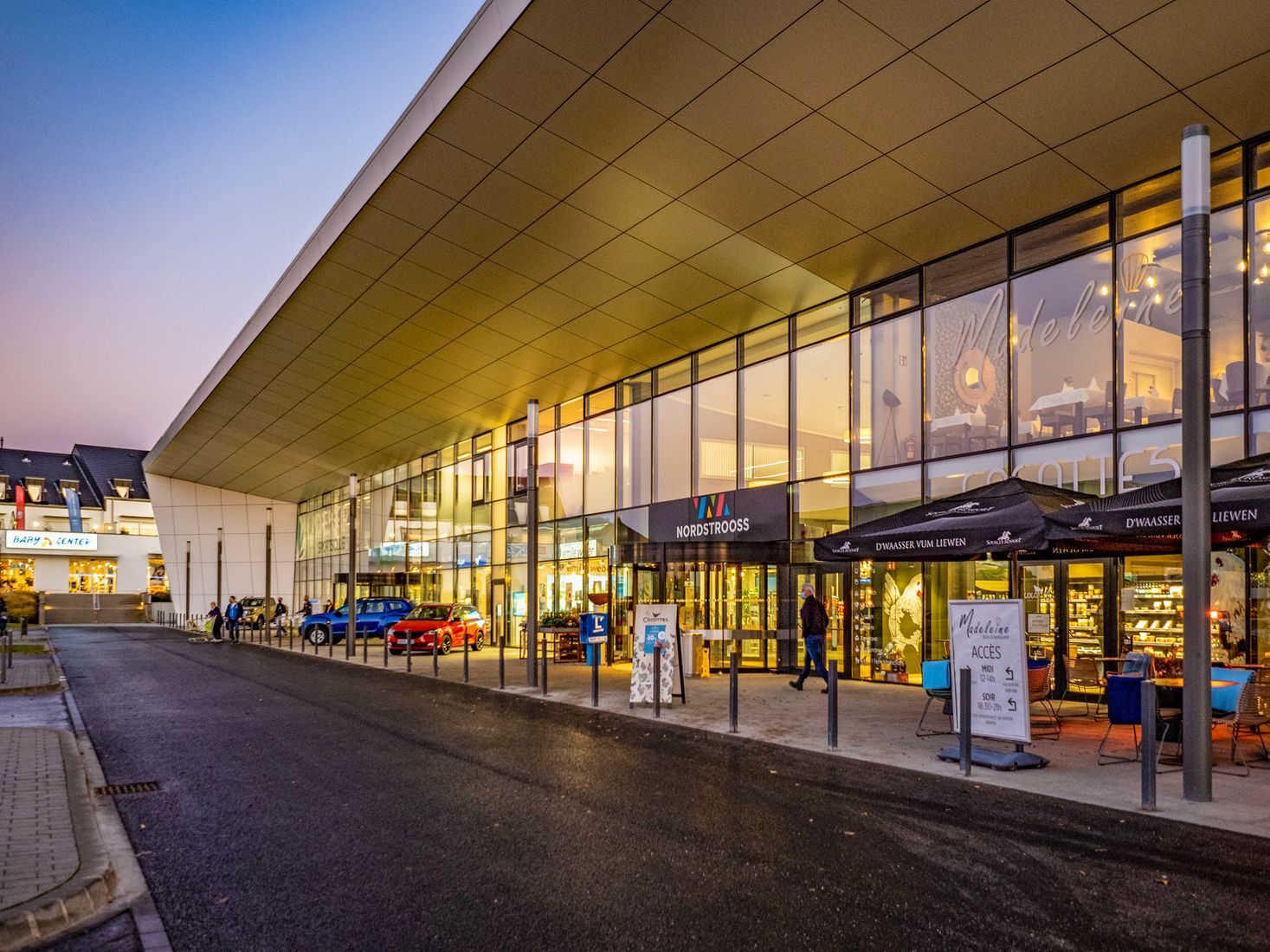 Eine Aufnahme des Außenbereichs der "Shopping Mile Nordstraße", wie das Einkaufszentrum offiziell heißt. Das Foto wurde bei Dämmerung aufgenommen, und das Einkaufszentrum in Manach bietet eine Vielzahl großartiger Einkaufsmöglichkeiten.