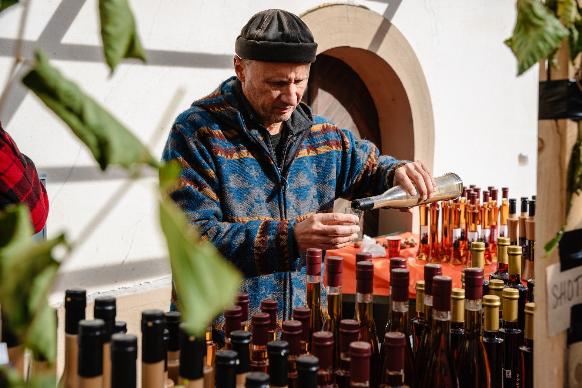 Man selling his local liquors at the Nut Market in Vianden, Éislek, Luxembourg, and pouring a glass for tasting. 