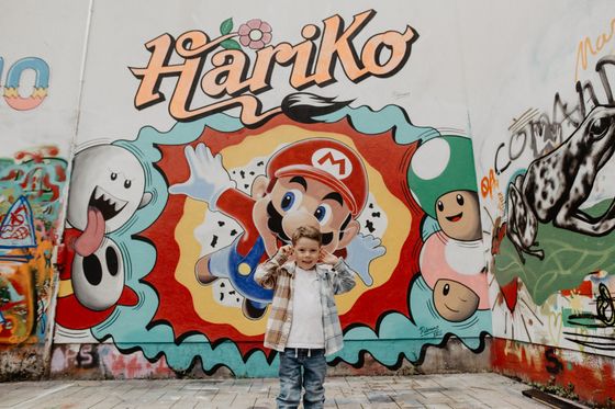 Un petit garçon se tient devant un graffiti de Hariko à Ettelbruck.