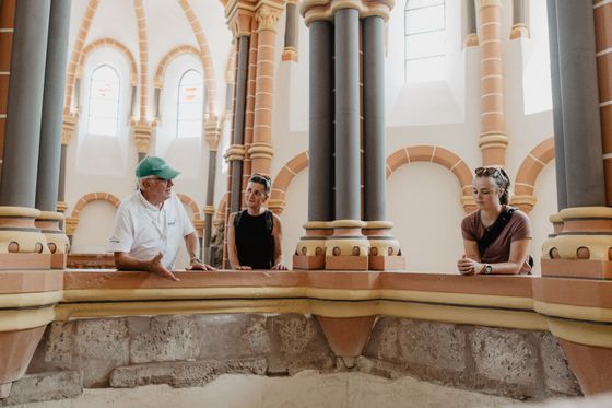 Bezoekers nemen deel aan een rondleiding in een historisch gebouw in Vianden met decoratieve zuilen en architectuur