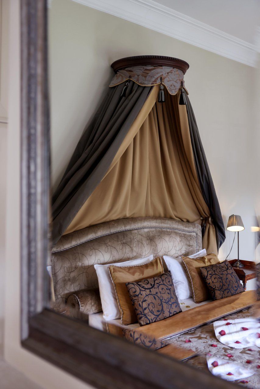 Foto van een bed in kasteelstijl met een bruine deken en verfijnd kant in een kamer van Château d'Urspelt.