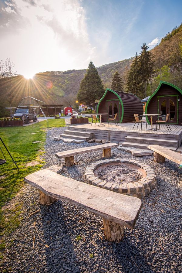 Een vuurplaats op Camping du Nord in Goebelsmühle, met kleine houten huisjes op de achtergrond.