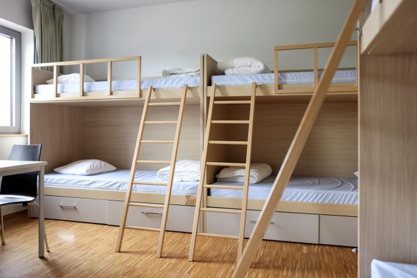 Een kamer in de jeugdherberg van Weicherdange met stevige houten stapelbedden en eenvoudige inrichting.