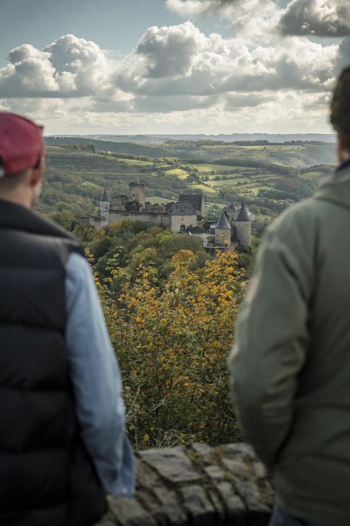 Zwei Männer genießen den herbstlichen Ausblick vom Aussichtspunkt Gringlee auf dem Lee Trail im Éislek, Luxemburg. 