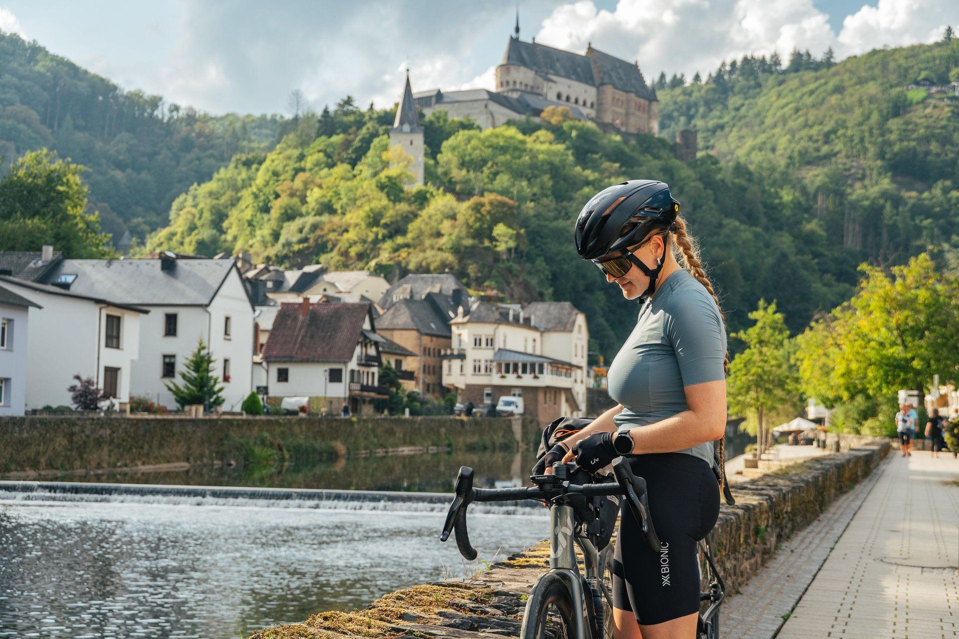 Radfahrer auf einer Brücke in Vianden mit der Burg Vianden im Hintergrund