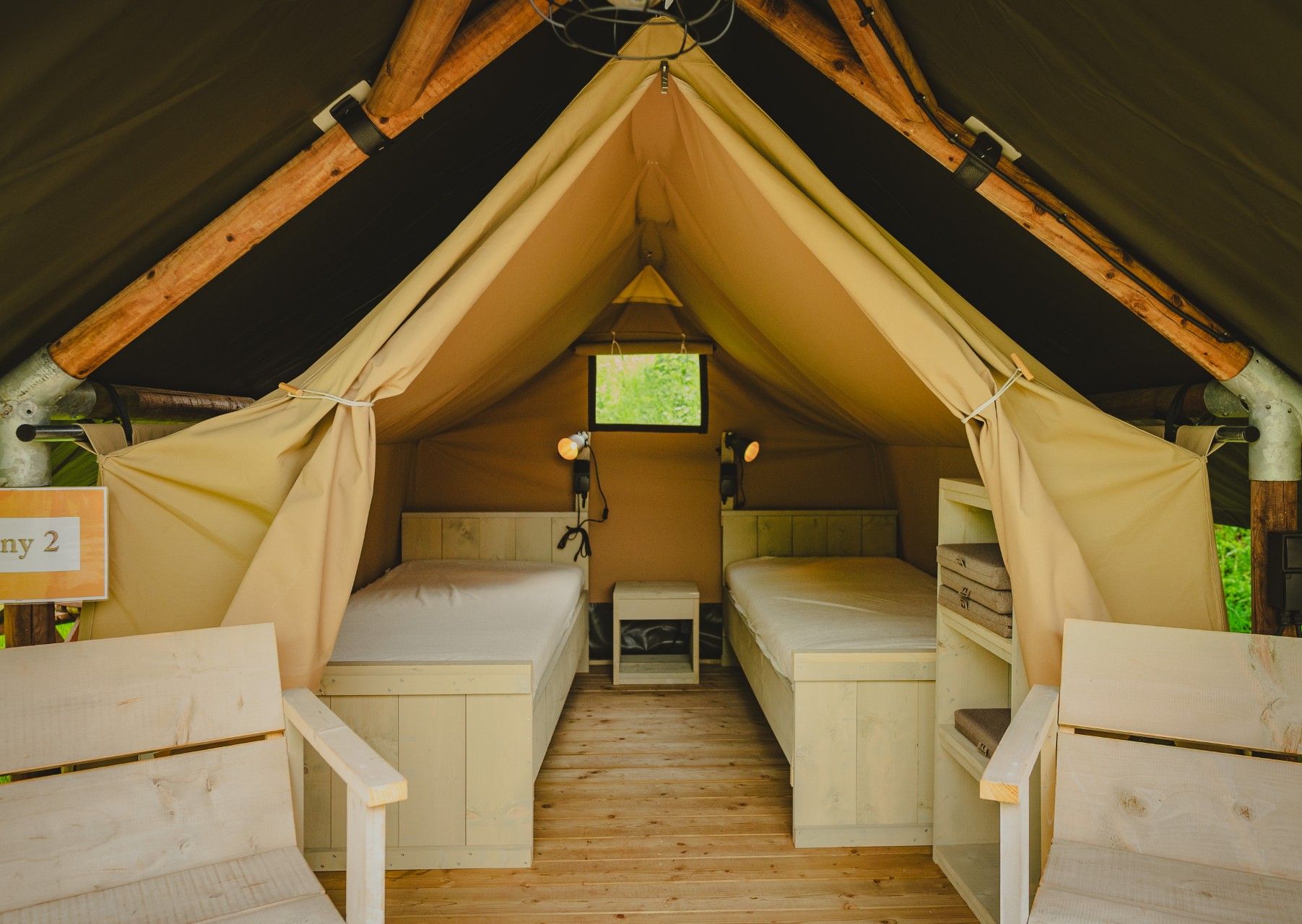 Interior view of a furnished glamping tent with beds and wooden structure at Camping Ettelbruck