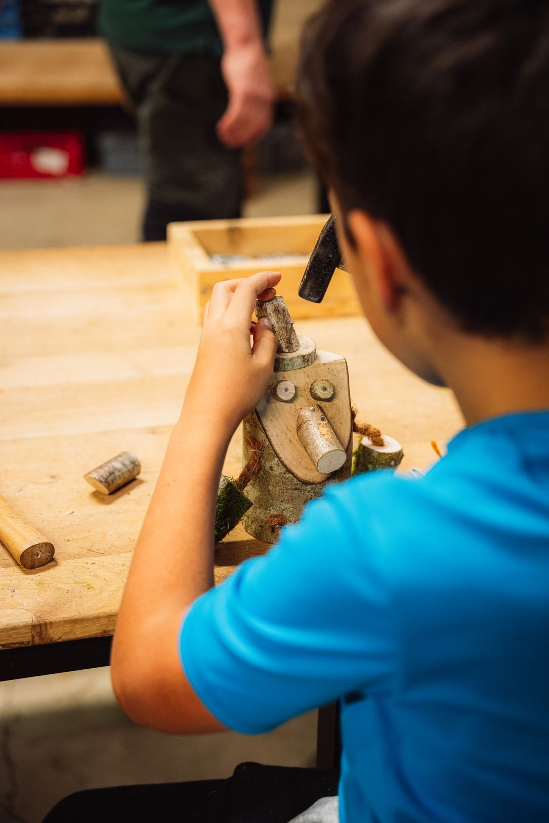 Kid carving wood and creating a wooden sculpture for the Trauliicht tradition at Robbesscheier in Munshausen, Éislek, Luxembourg.