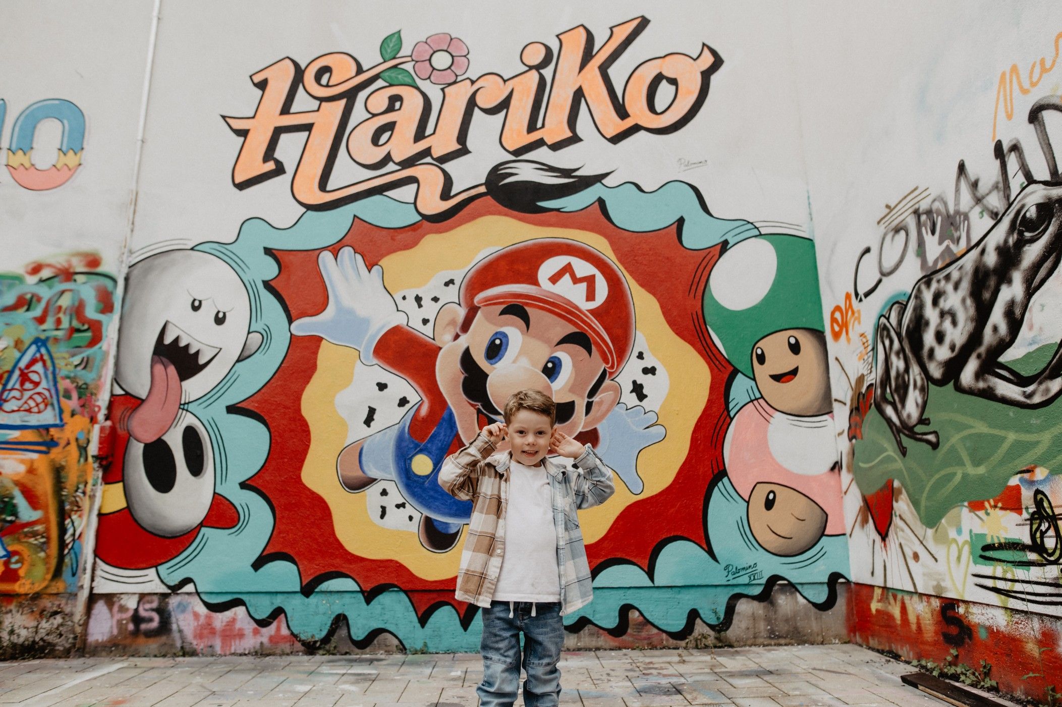 Un petit garçon se tient devant un graffiti de Hariko à Ettelbruck.