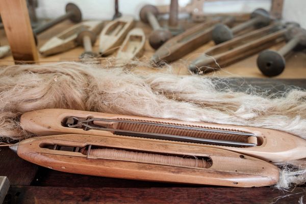 A historic wooden weaving tool with wool beside it – a glimpse into traditional craftsmanship.