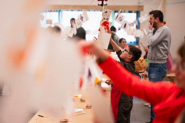 Des enfants accrochent et observent des papiers éparpillés lors d’une activité créative au musée pour enfants PLOMM.