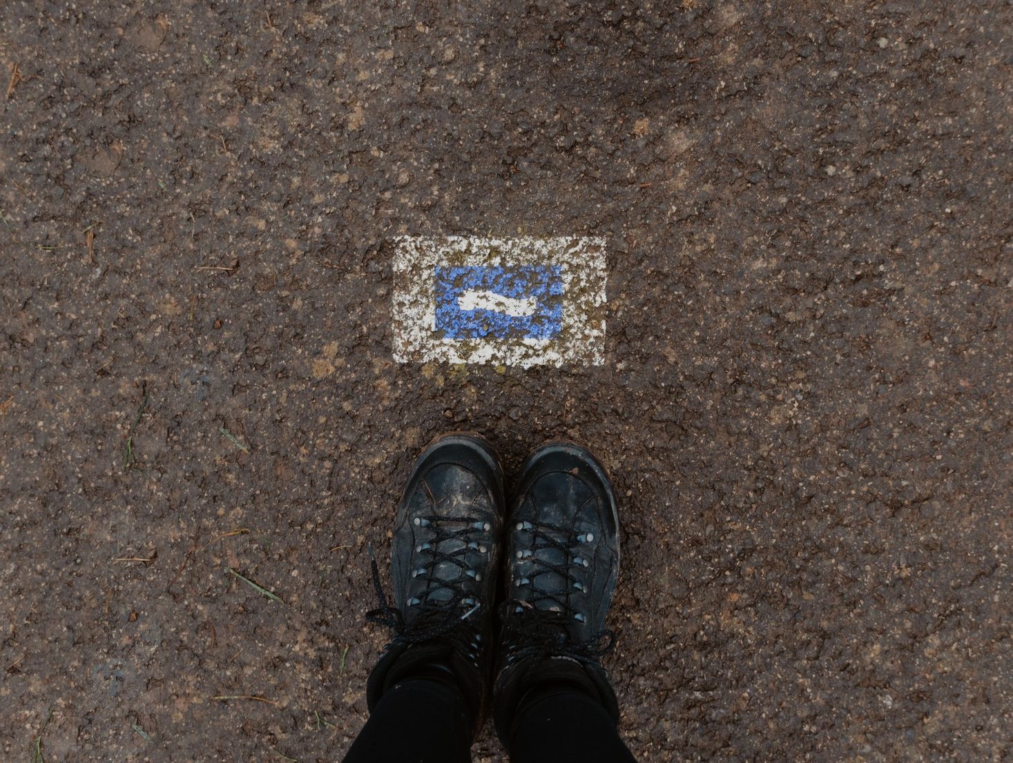  Zwei Füße stehen neben einem Wegweiser des Escapardenne Lee Trails in Luxemburg. 